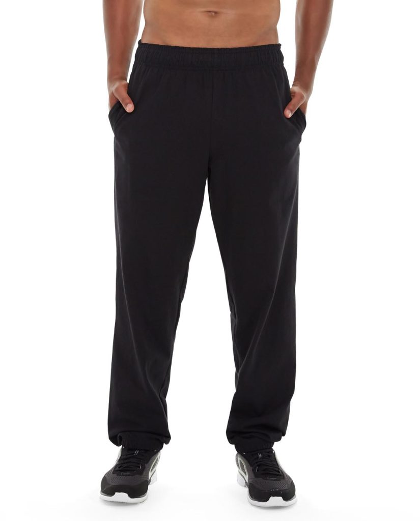 Male yogi wearing black Cronus Yoga Pants, stretching in a relaxed pose