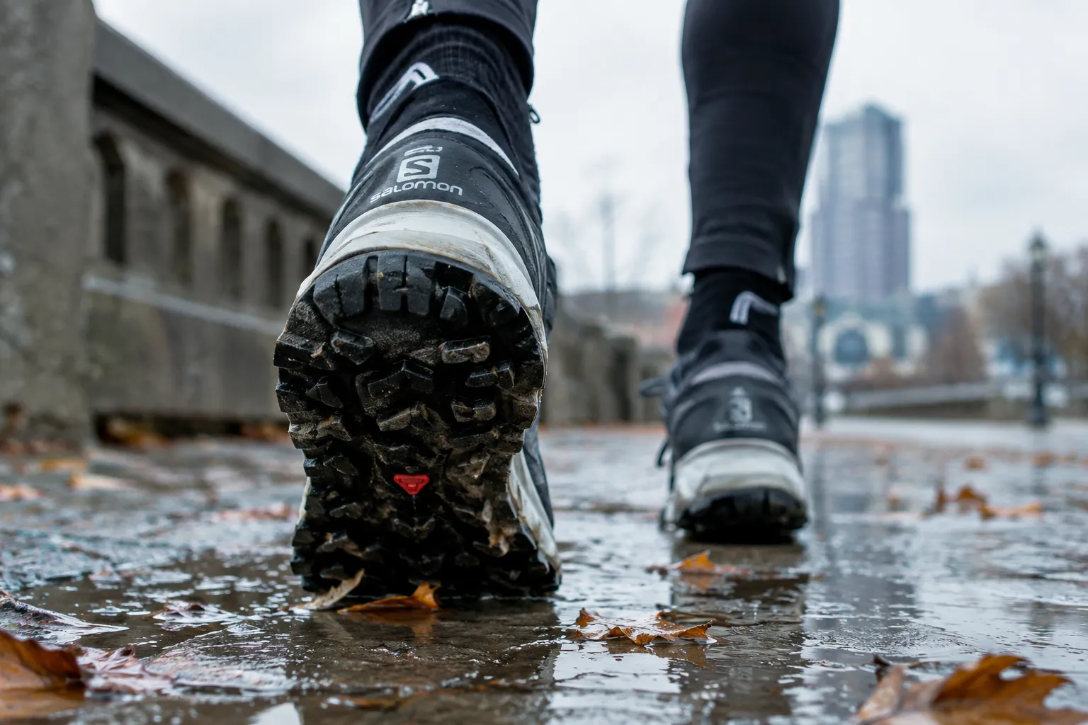 Runner wearing winter running shoes on a wet autumn sidewalk